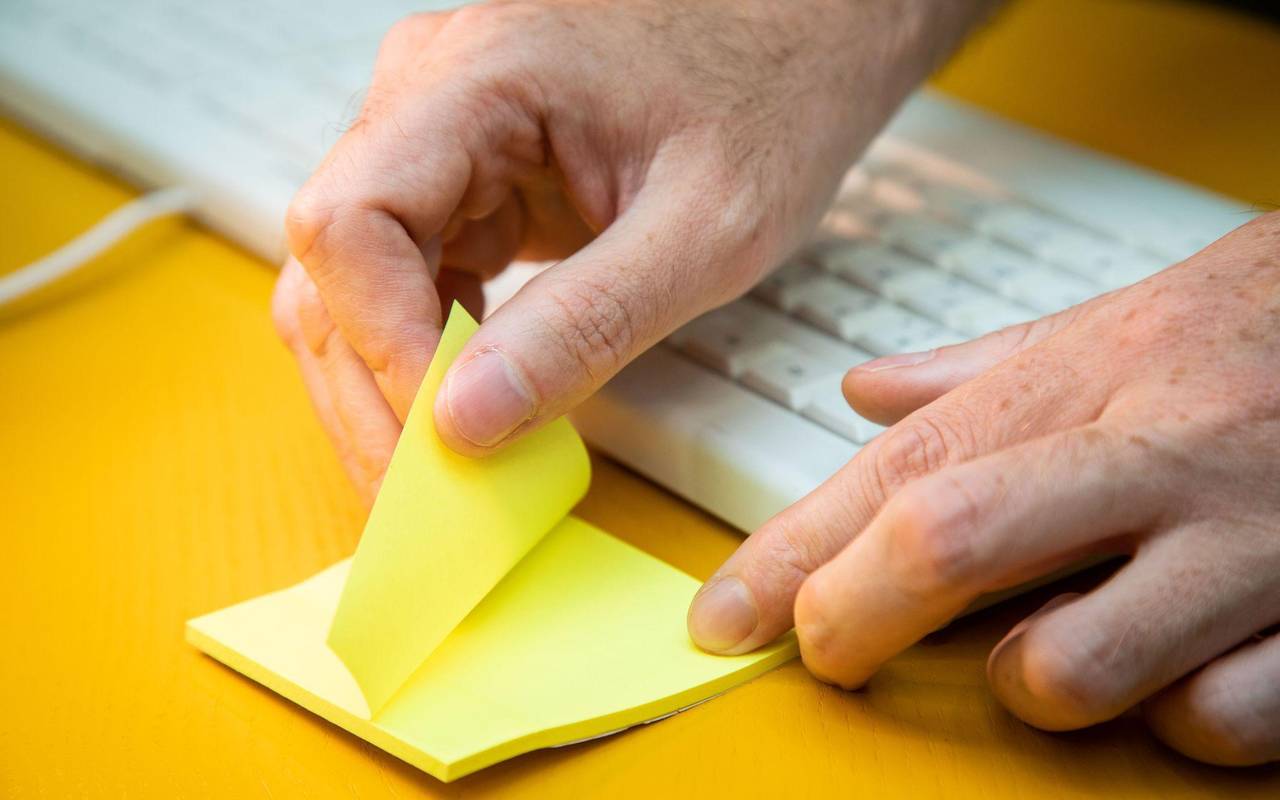 Mann reißt einen Klebezettel von einem Block