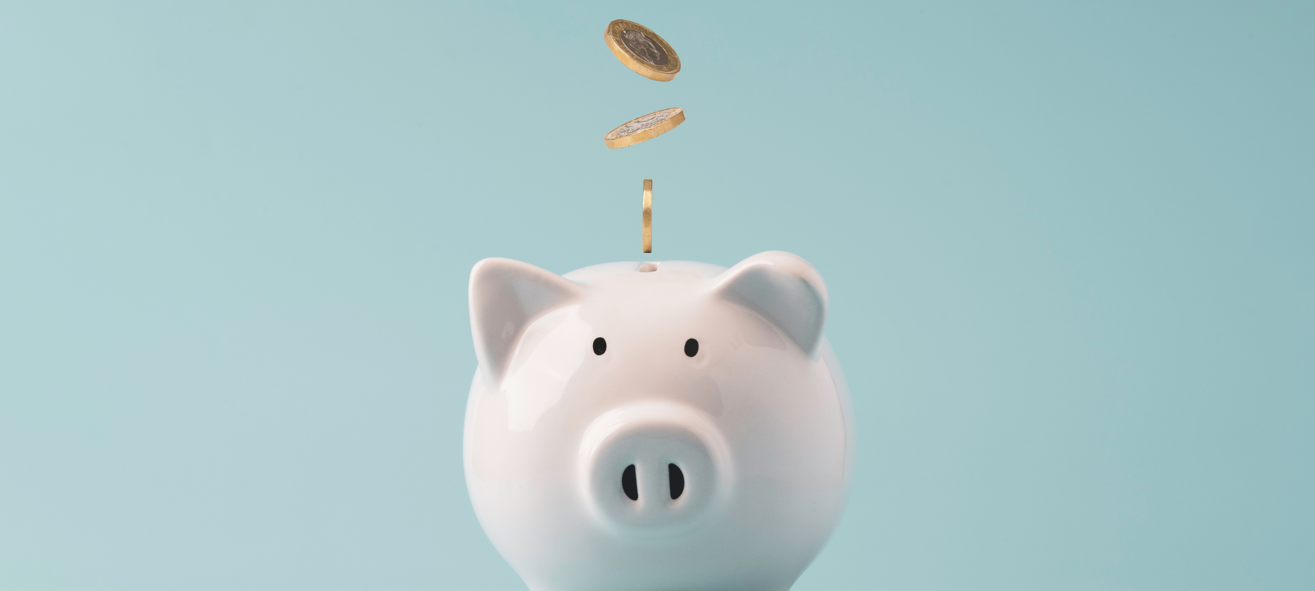 Minimalismus / weißes Sparschwein mit Kleingeld, hellblauer Hintergrund